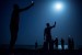 Gente de noche con telfonos apuntando al cielo.
