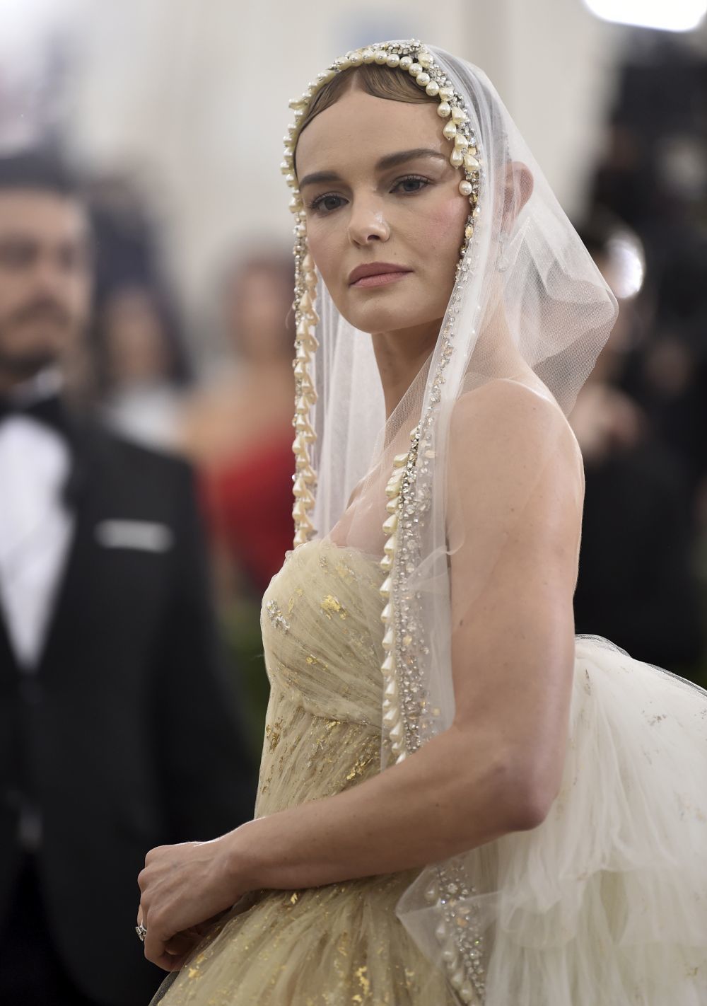 La actriz Kate Bosworth acompaña su vestido dorado con un velo de tul...