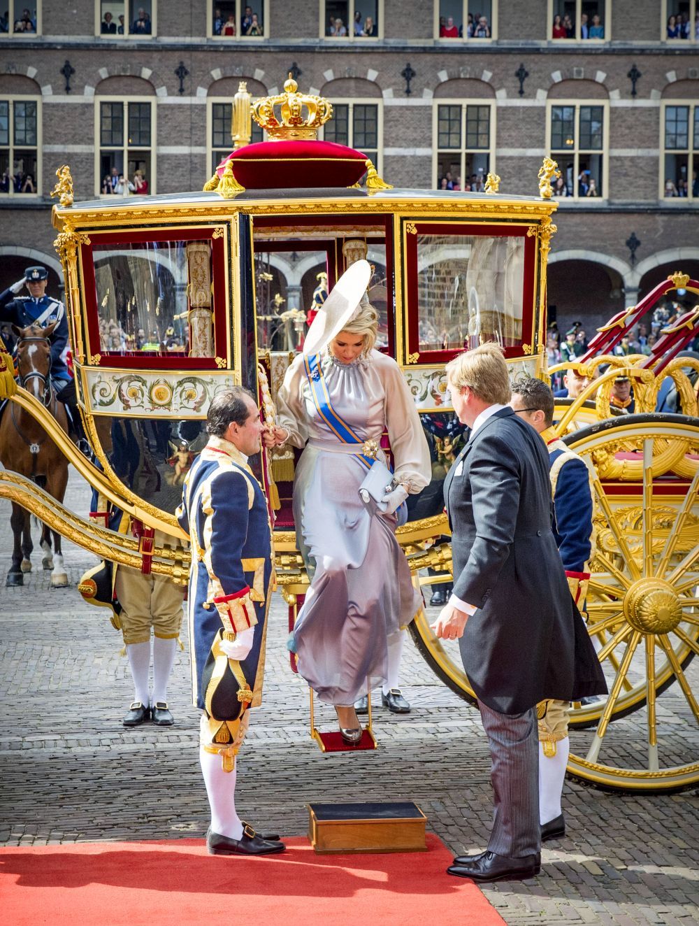 La reina llegando en una gran carroza dorada.