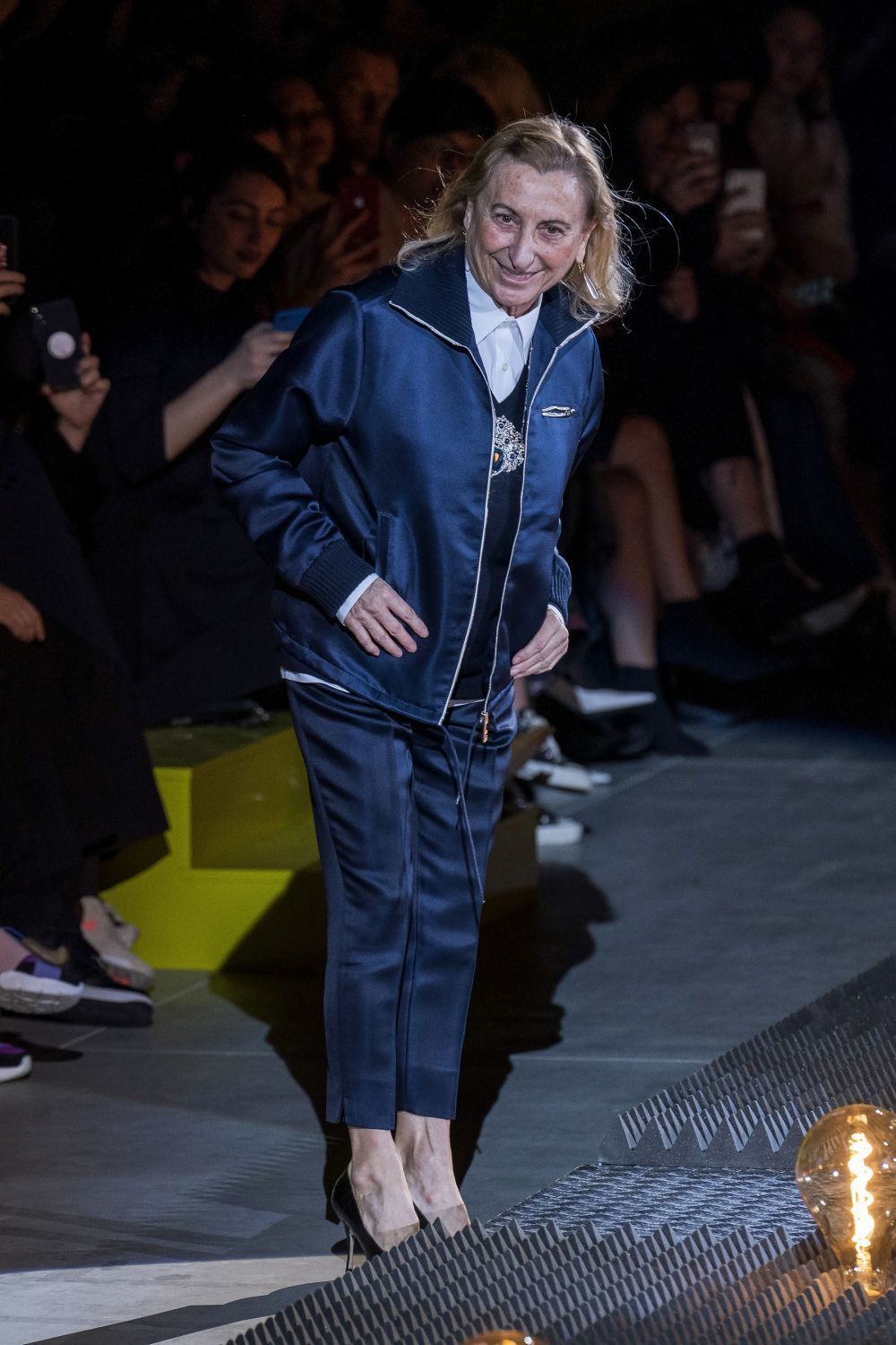 Miuccia Prada salía a saludar a los asistentes de su último desfile en Milán llevando un presagio encima