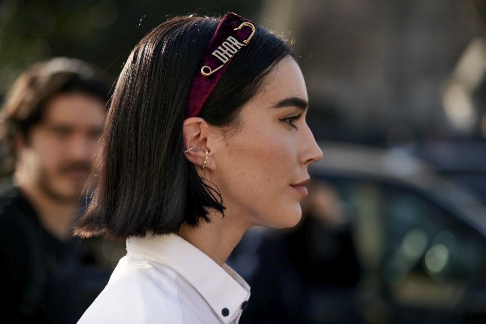 En el street style de París, hemos visto diademas de terciopelo como esta en tono burdeos y con broche imperdible con logo de Dior.