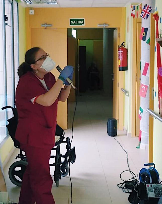 Araceli Aranda animando a los mayores, micro en mano, por los pasillos de la residencia.