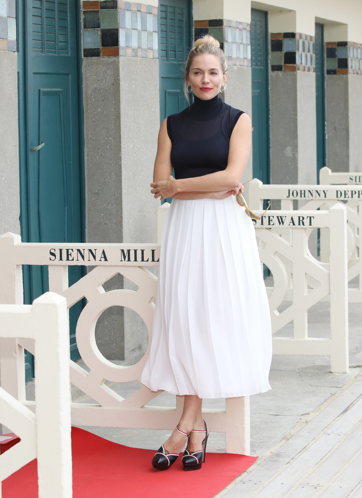 Sienna Miller con falda midi blanca y top azul marino.