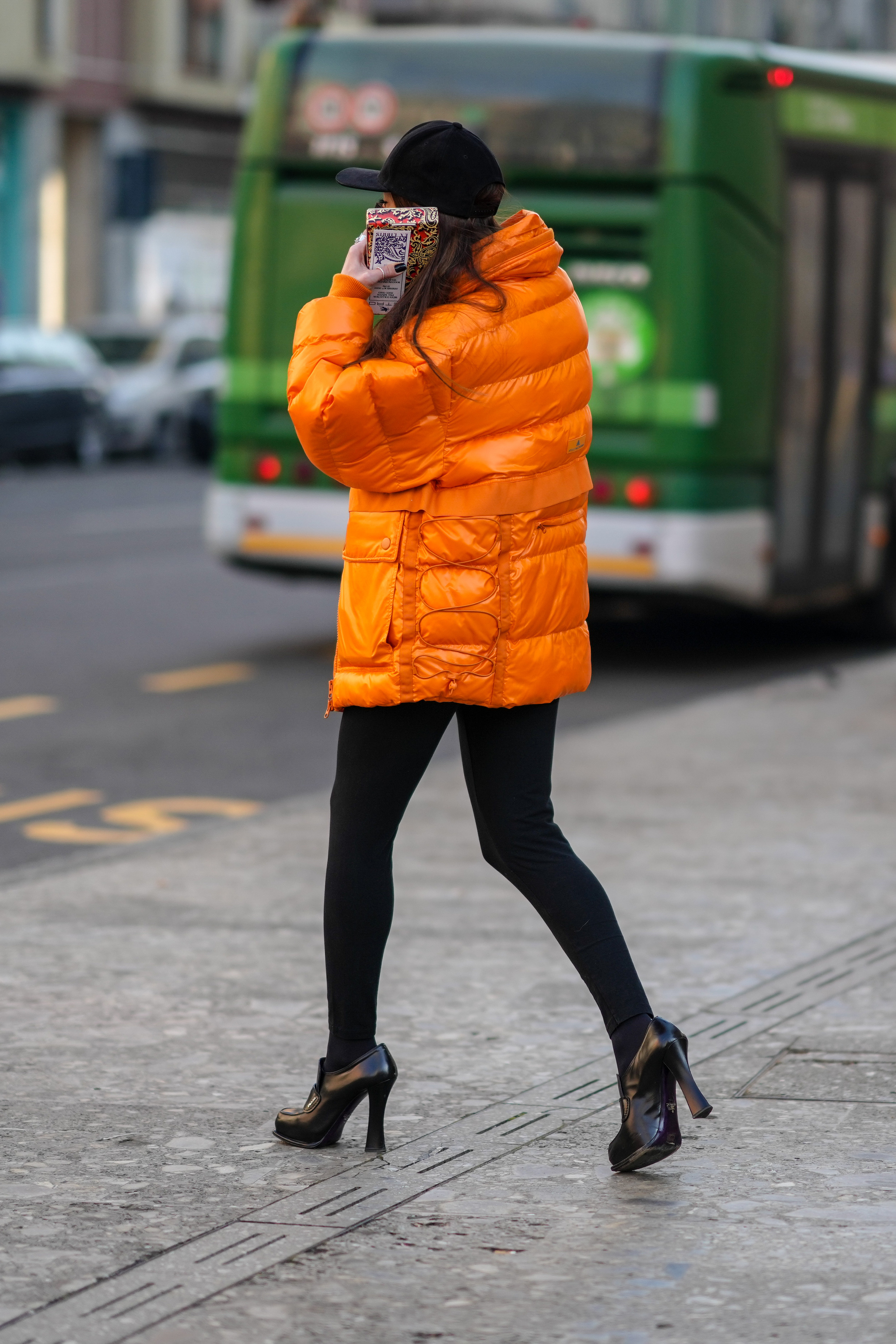 Una invitada con un plumas naranja por las calles de Milán.