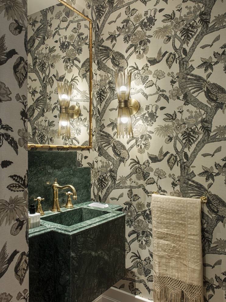 Para el cuarto de baño de invitados se diseñó una pila de mármol verde y un espejo con marco de latón que simula bambú. El aplique es de Eichholtz.