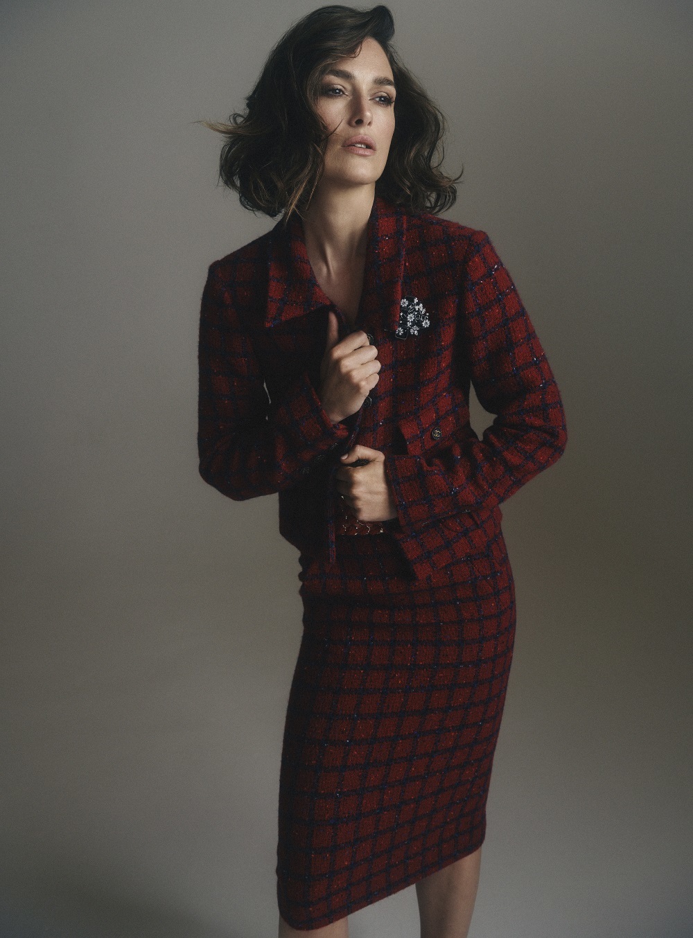 Keira Knightley con traje de chaqueta de tweed de lana rojo y azul con broche en metal y resina, Chanel.