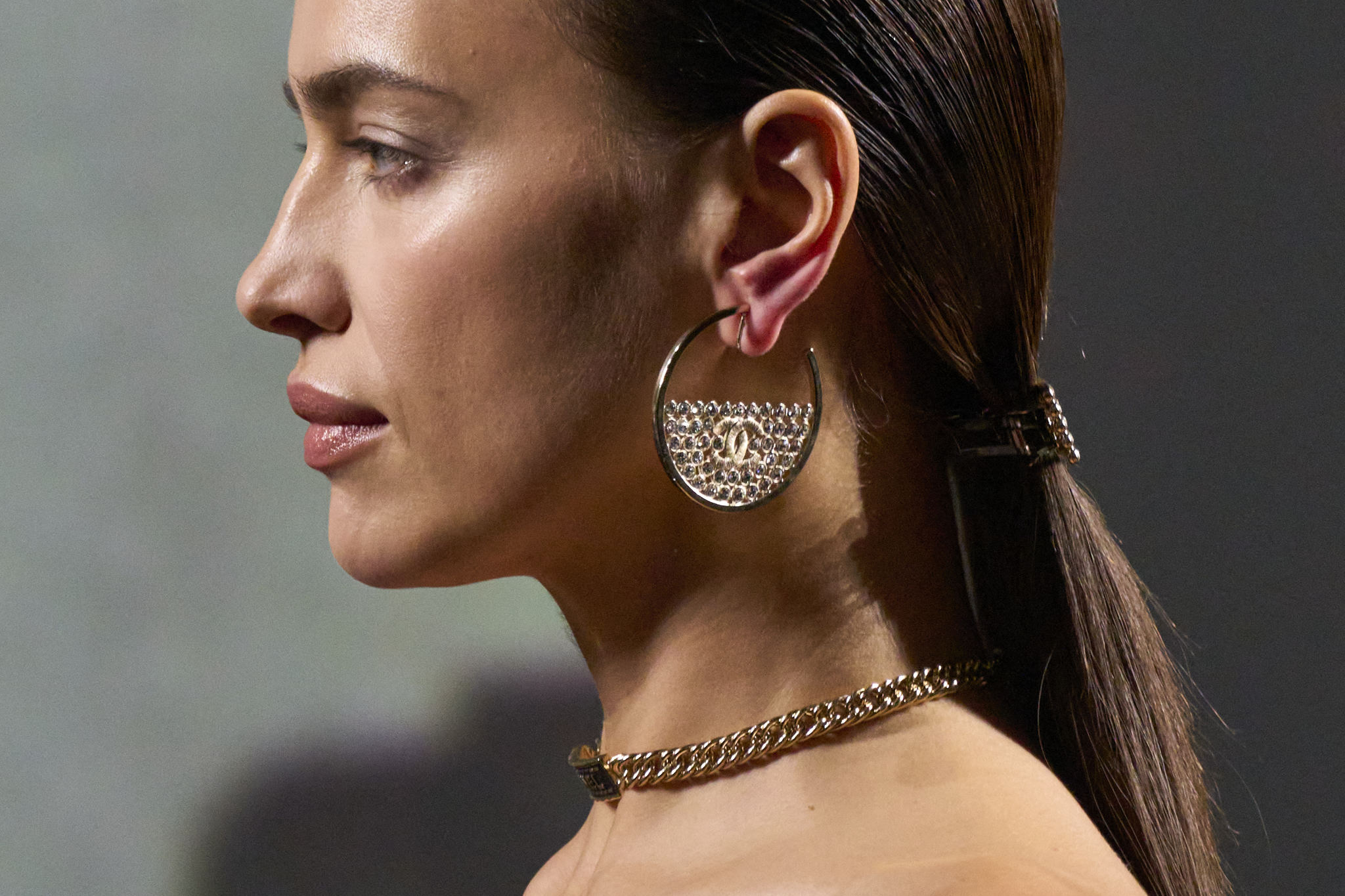 Los pasadores y las coletas bajas como la que luce Irina Shayk se combinan con maxipendientes y un maquillaje luminoso y natural en el desfile de Chanel primavera verano 2023.