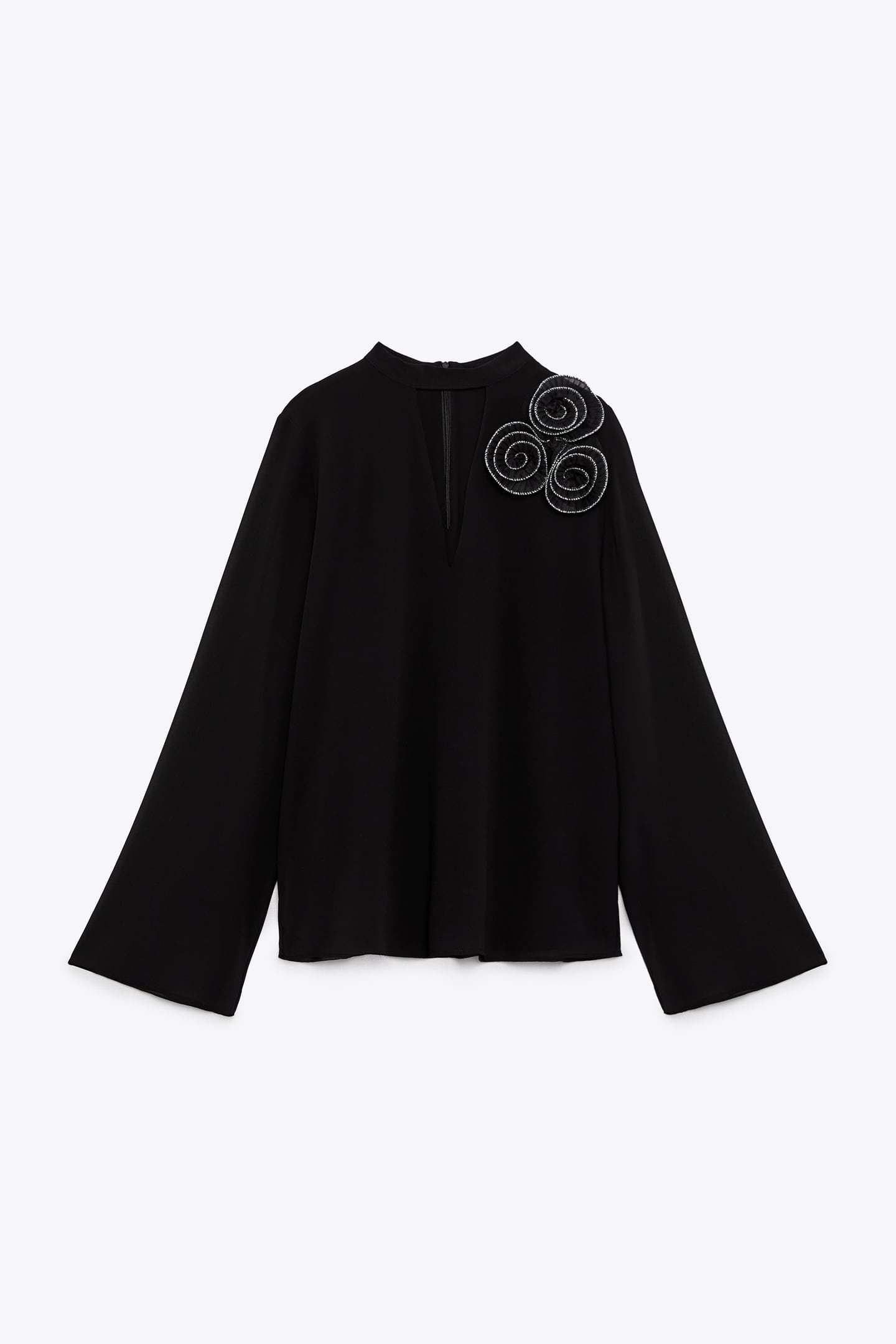 Blusa negra con flores en el hombro, de Zara.