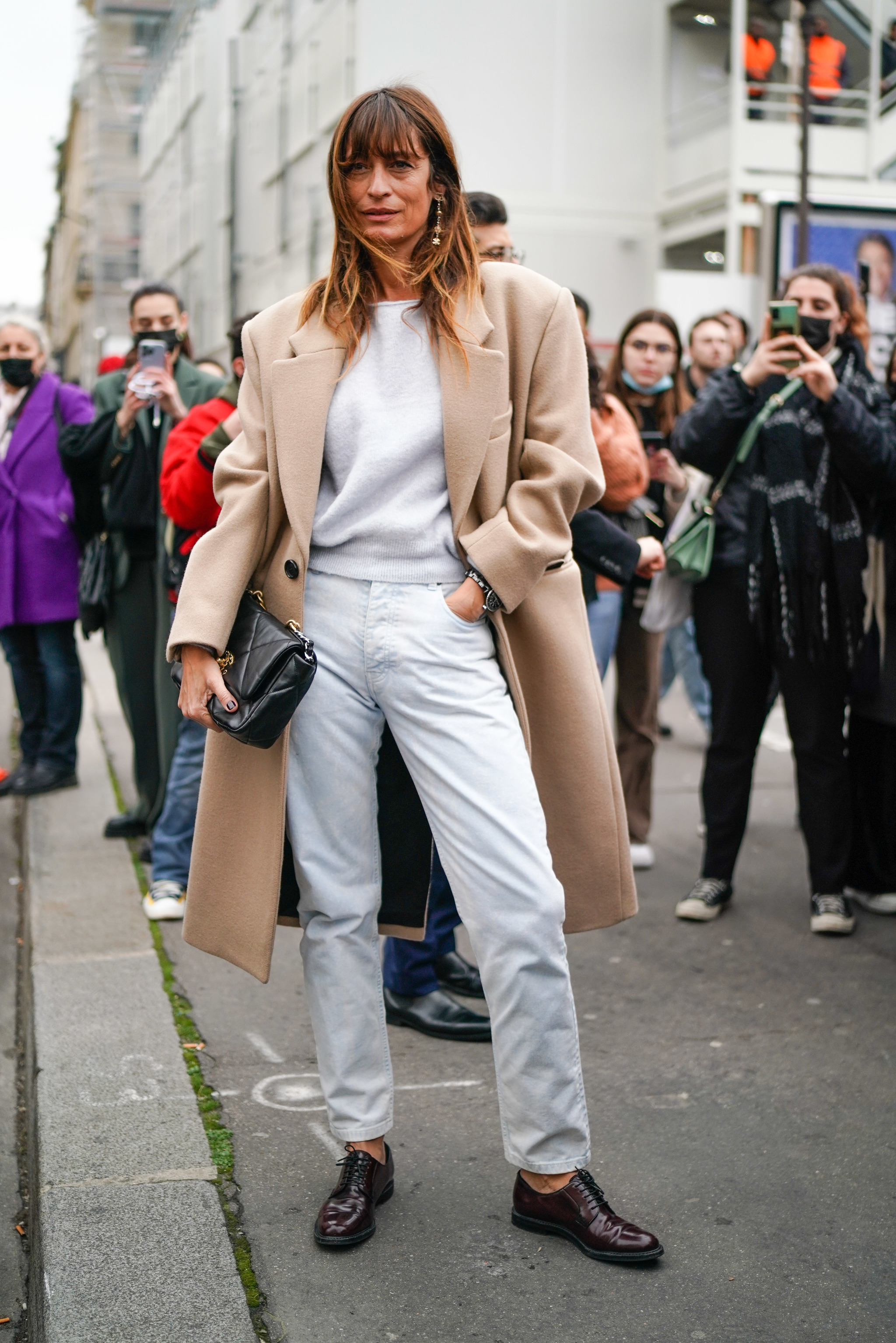 Caroline de Maigret con jeans blancos y abrigo camel.