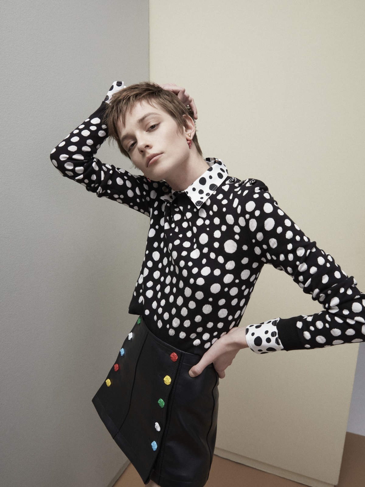 La modelo Sophie Dominique con camisa de seda y jersey Infinite Dots, minifalda de piel con botones esculturales y pendientes Louisette, todo de la colección Louis Vuitton x Yayoi Kusama.