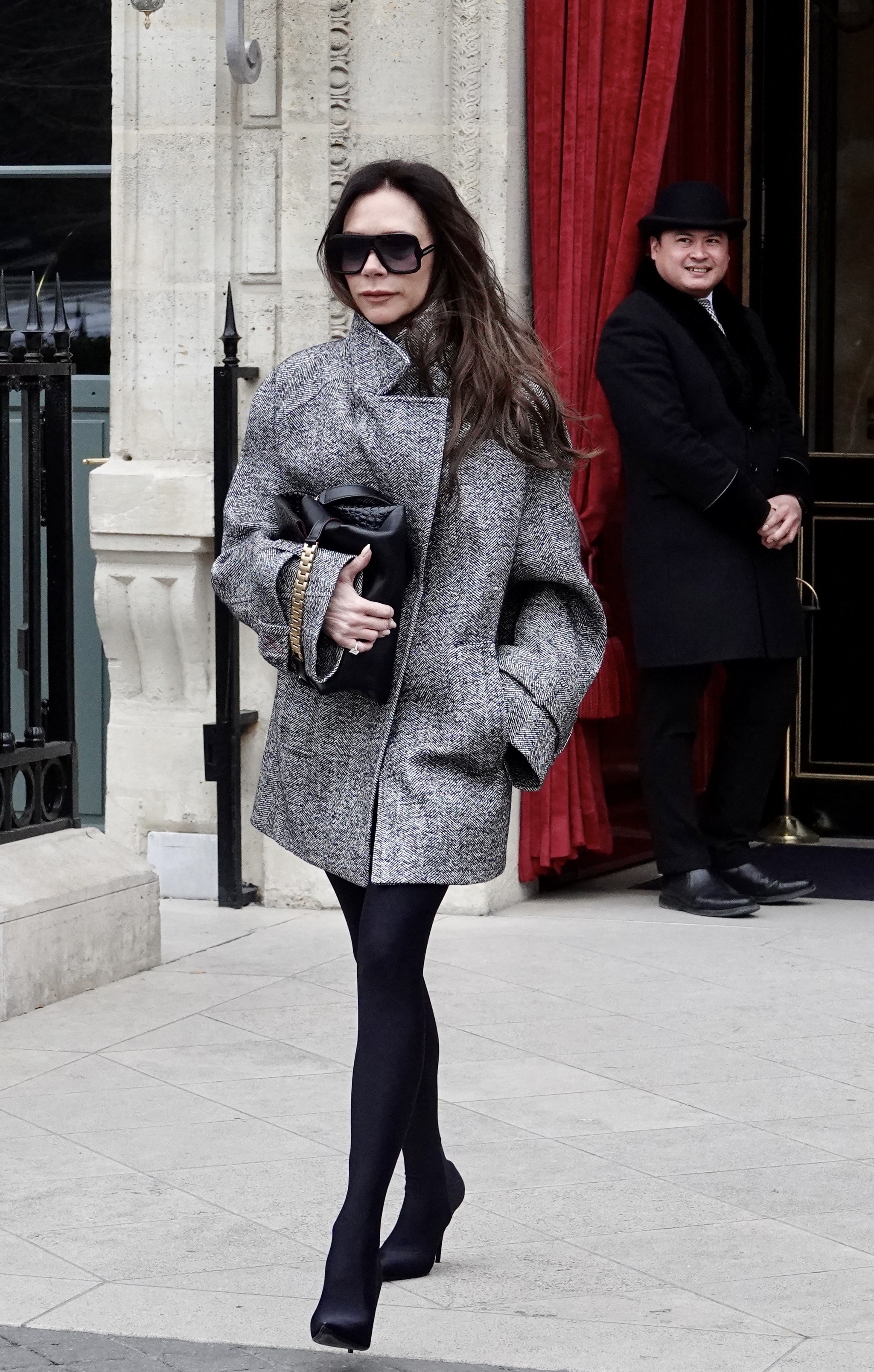 Victoria Bechkam con chaquetón gris y leggings-botas negros.