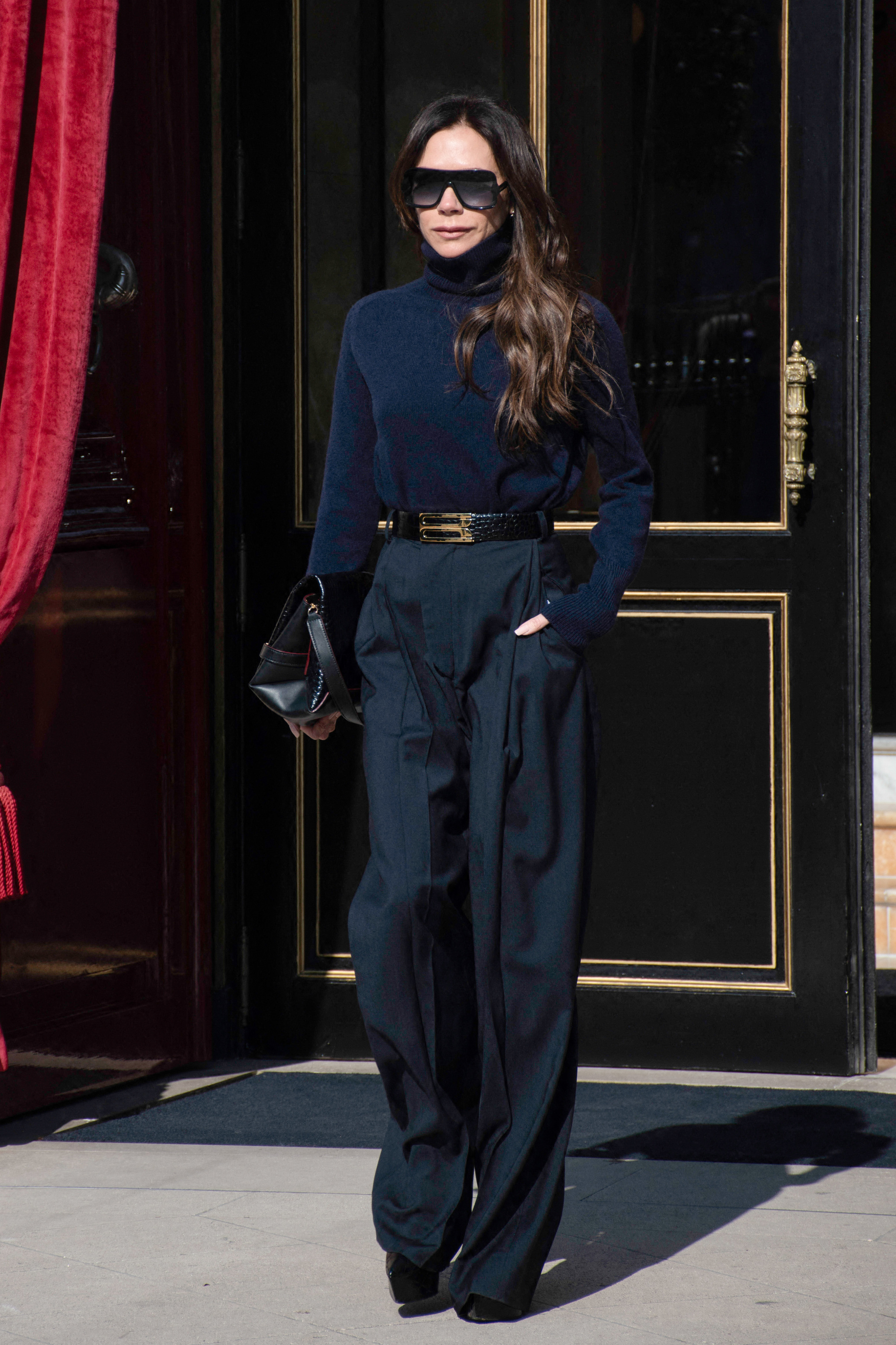 Victoria Bechkam con pantalón ancho y jersey de cuello vuelto azul marino en París.