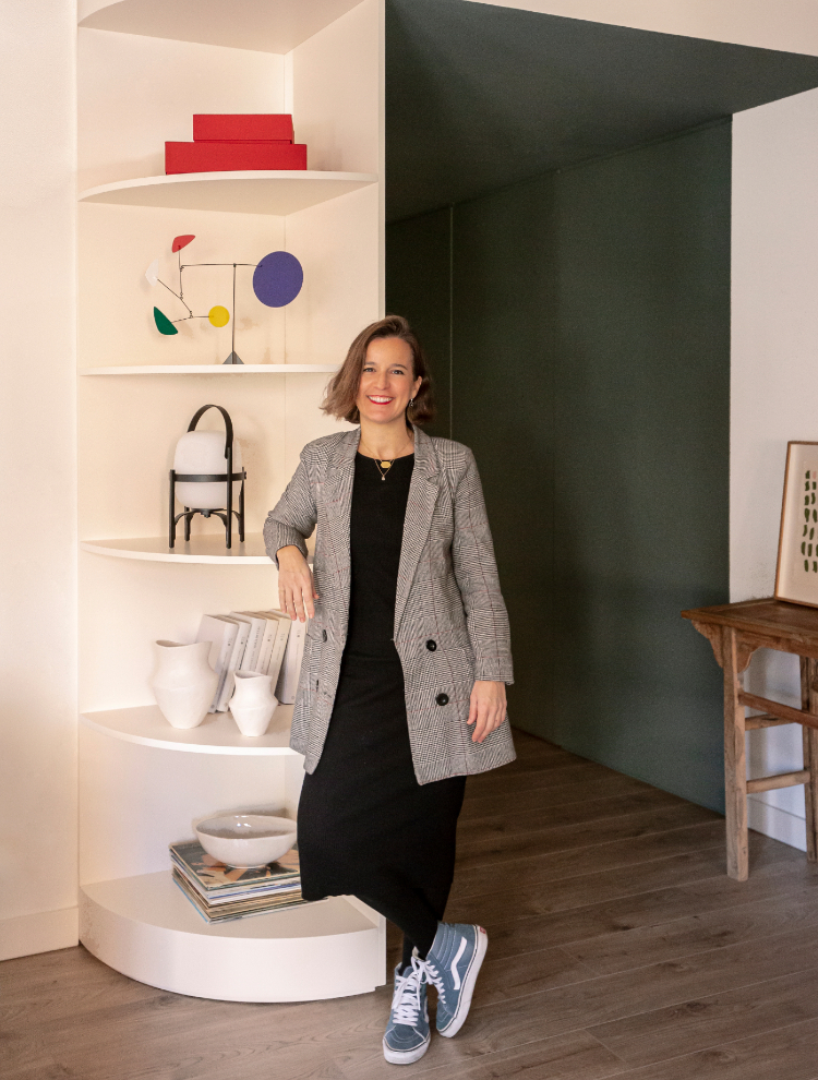 La interiorista Bárbara Aurell, ante la estantería curvada del salón, donde destaca la mini cesta negra de Santa & Cole para Avanluce