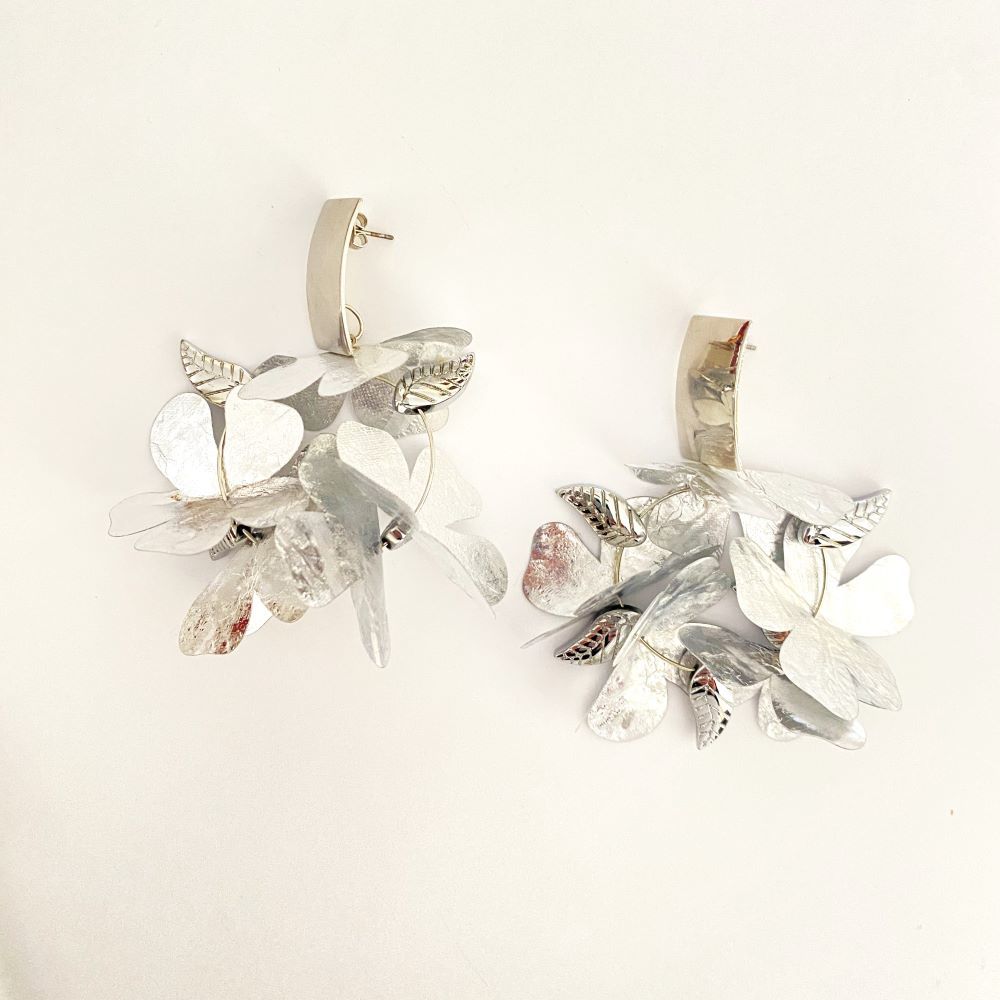 Pendientes de aro con flor plata, de Lamágora (30 euros).