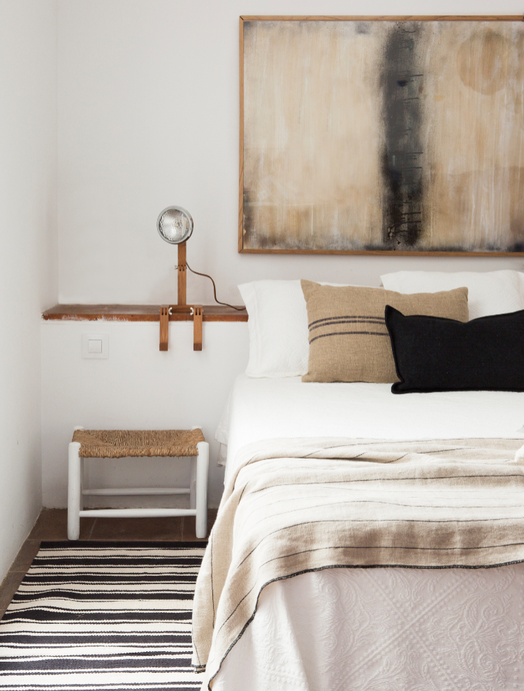 Un rincón del dormitorio donde se aprovecha la repisa de obra y textiles de lino en tonos naturales.