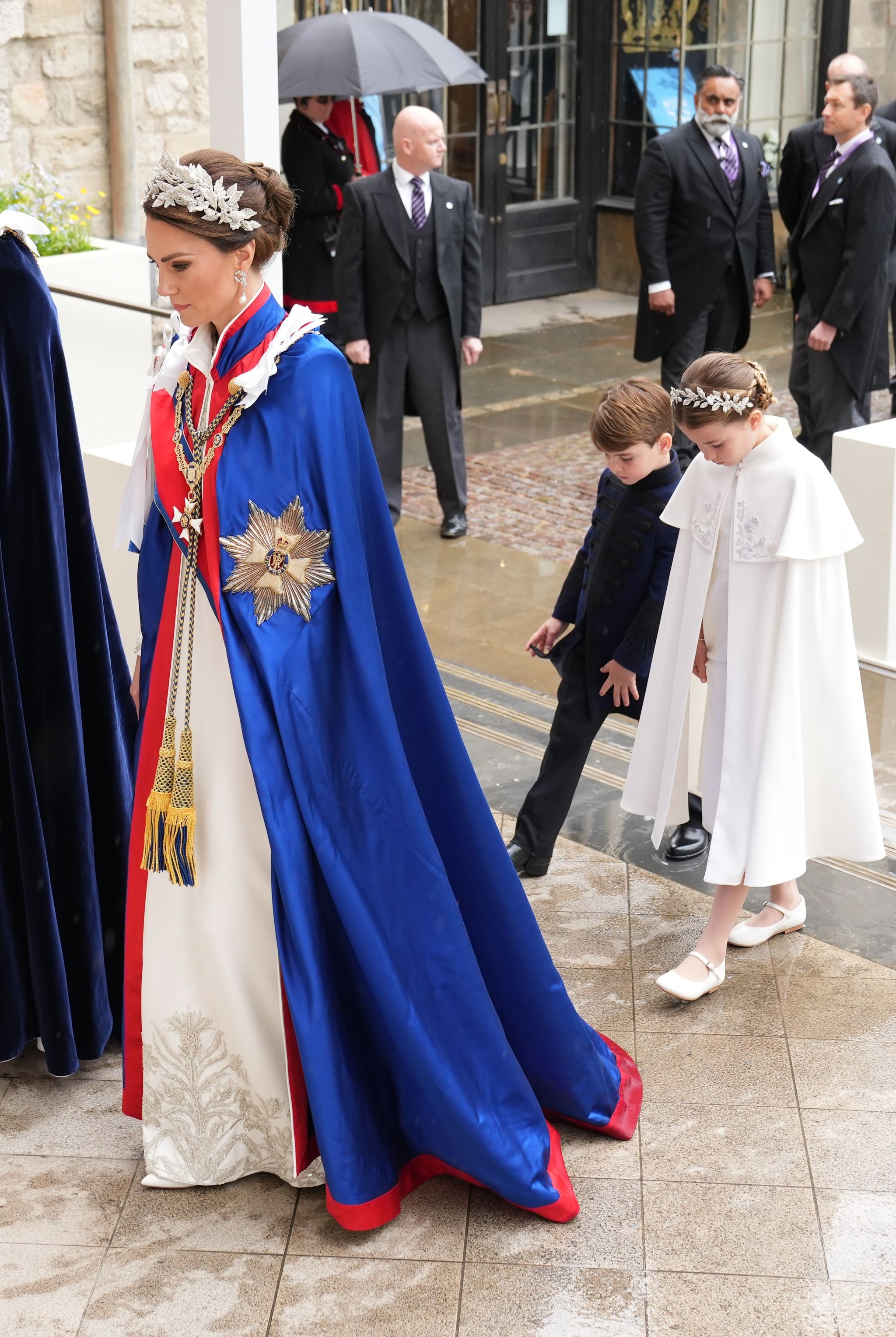 Kate Middleton con vestido blanco con capa azul en la entrada a la abadía de Westminster para la Coronación de Carlos III.