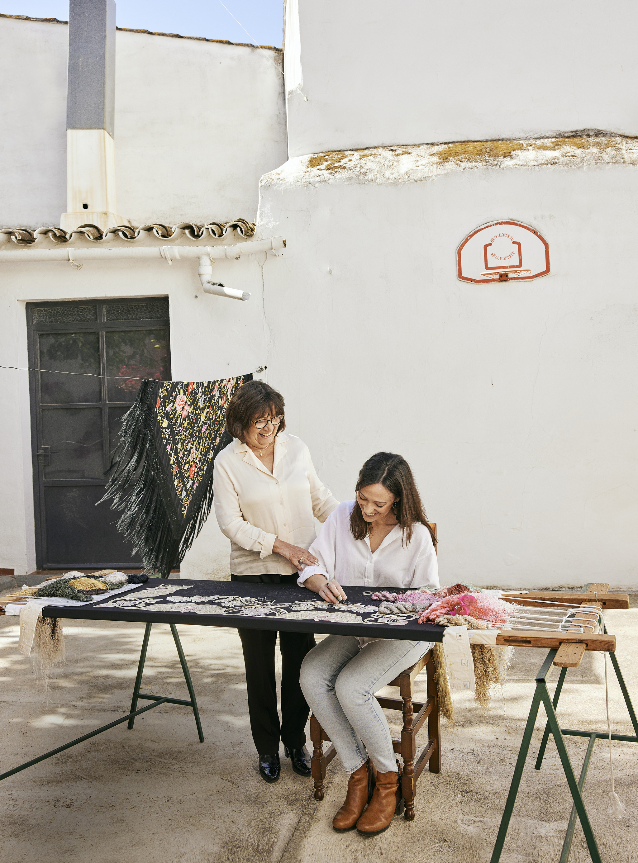 Manuela Romero y su hija Fátima bordando un mantón en el patio de su casa en Carrión de los Céspedes (Sevilla).