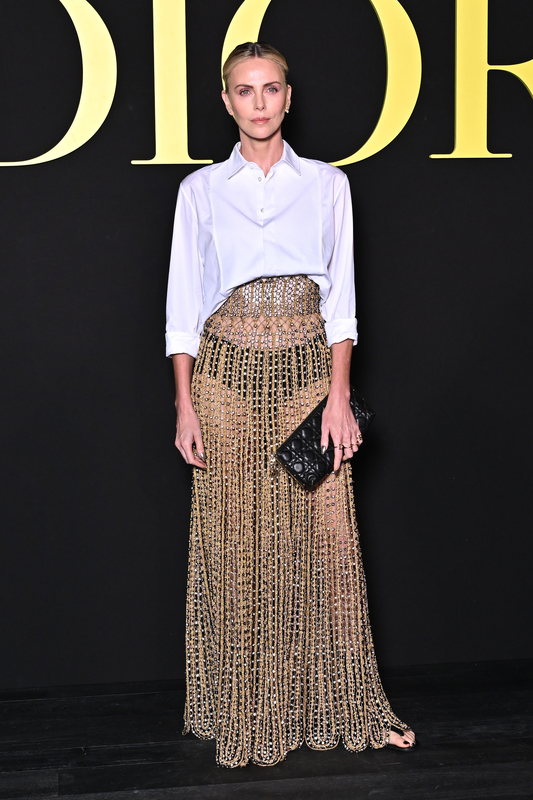 El look de Dior de Charlize Theron: camisa blanca y falda dorada.