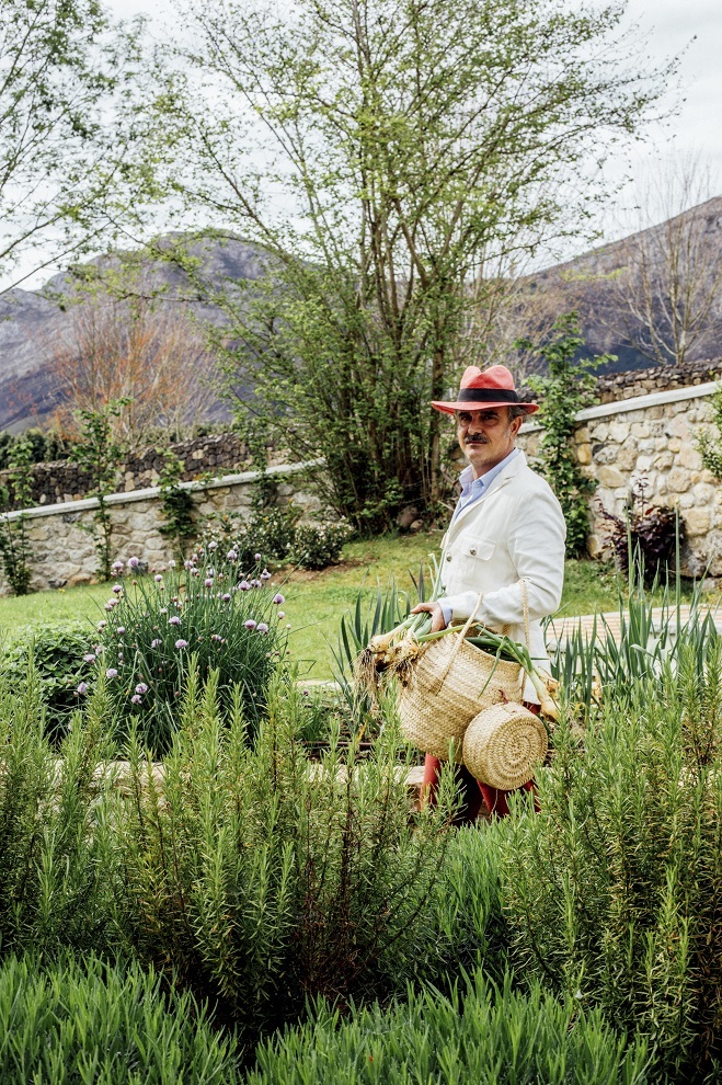 Lorenzo cosecha cebolletas de su huerta, rodeada de plantas aromáticas. El cesto es de Sense Nom, en Mahón.
