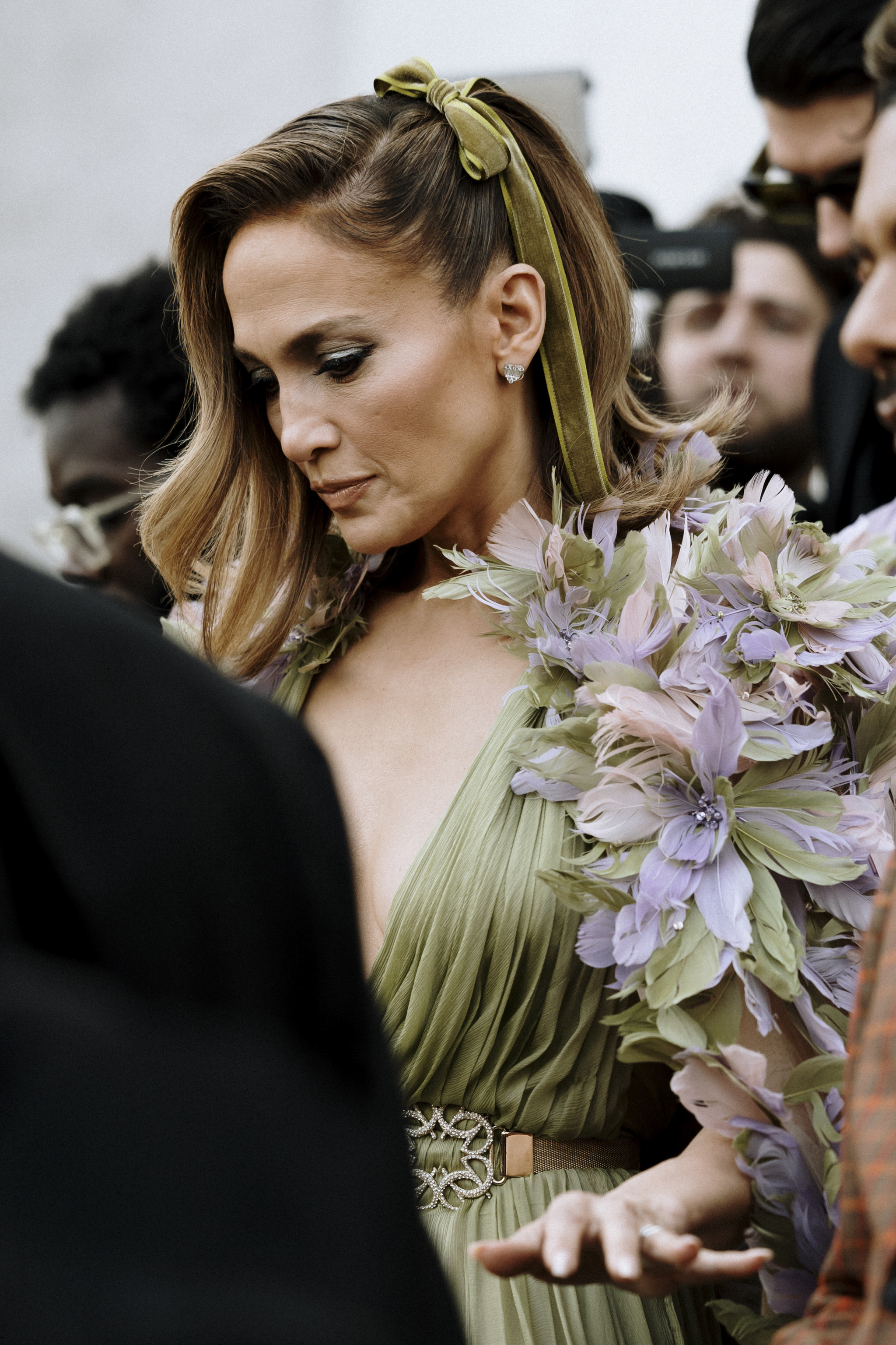 Jennifer Lopez con un semirrecogido con lazo verde de terciopelo en el street style de París.