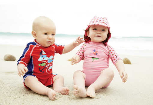 Niños pequeños sentados en la arena de la playa