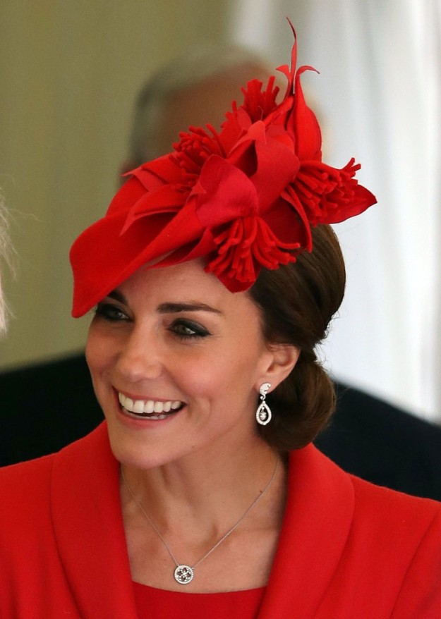 Kate Middleton con tocado rojo y cabello recogido en un moo bajo clsico.